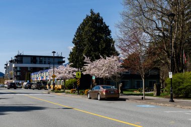 SQUAMISH, CANADA - 13 Nisan 2025: Dağlık mavi gökyüzünde küçük bir kasabada şehir yolları ve binalar