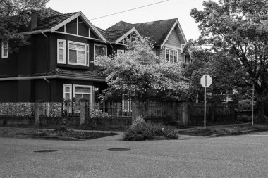 VANCOUVER, CANADA - MAYIS 01, 2025: Kuzey Amerika 'da baharda banliyöde siyah beyaz evler. Güzel manzaralı lüks evler. Güzel ağaçları olan şehir caddesi.