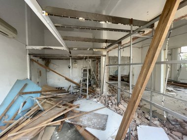 Açığa çıkmış metal iskeleti, ahşap kirişleri, döküntüleri ve döküntüleri olan eski bir binanın içinde. İnşaat alanı içerisi, ev tadilatı, yıkım süreci, tamamlanmamış iç mekan.