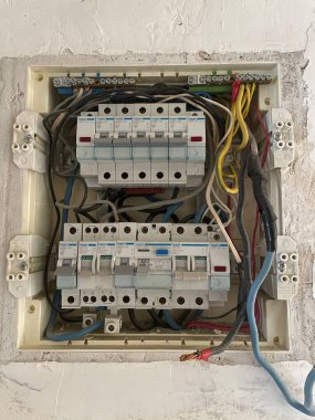Devre kesicileri, arta kalan akım cihazlarını (RCD), kablo bağlantılarını ve açığa çıkan bakır kabloları gösteren açık konut elektrik dağıtım panosu bir duvara yerleştirildi. Düzenli elektrik bileşenleriyle ev sigortası kutusuna yakın çekim