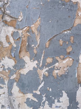 Eski alçı ve beton tabakalarını ortaya çıkaran mavi boyalı yıpranmış duvarın yakın çekimi. Sıkıntılı yüzey, düzensiz çatlaklar, pullar ve eski boya kalıplarıyla soyut bir grunge dokusu yaratır.