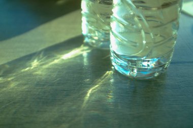 Masanın üzerinde güneş ışığı olan su şişesine yakın çekim. Yiyecek ve içecek konsepti. 