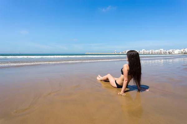 Mujer en bikini sentada en la playa — Foto de Stock
