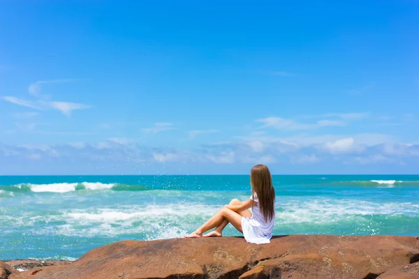 Mujer en vestido blanco sentado en la roca — Foto de Stock