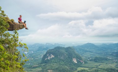 Dağlarda oturan dizüstü bilgisayar ile çalışan adam 