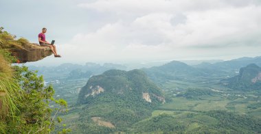 Kayalık dağ üzerinde oturan dizüstü bilgisayar ile çalışan adam 