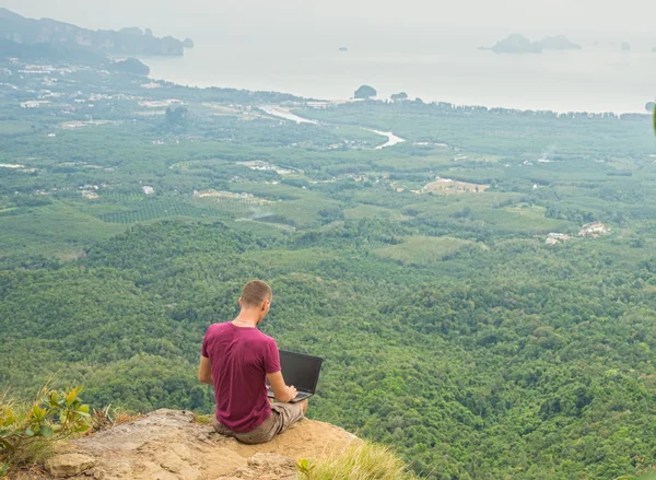 Человек, работающий с ноутбуком, сидящий на горе — стоковое фото