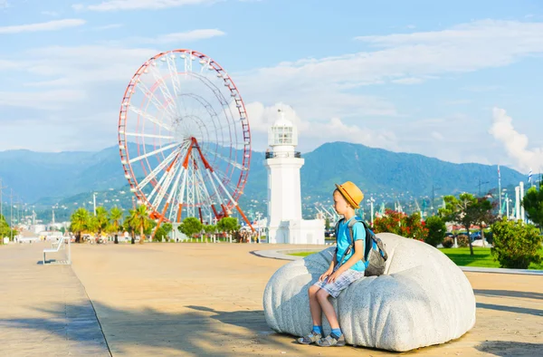 Boy with hat and  backpack  sitting on bench — Stock Photo, Image