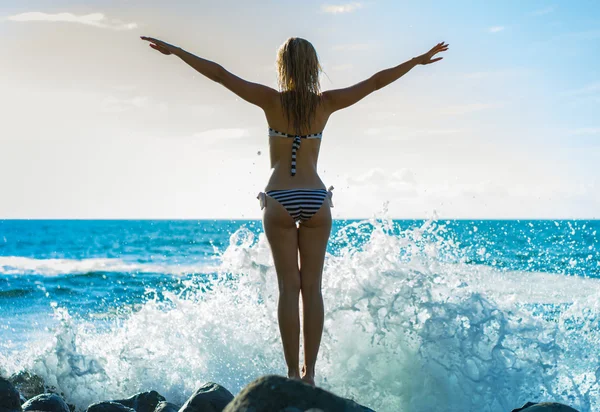 Jovem bela mulher de pé sobre as pedras quase ondas — Fotografia de Stock