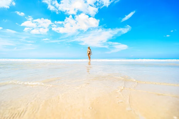 Mujer en bikini y gafas de sol caminando por la playa — Foto de Stock