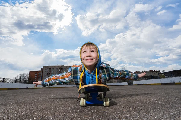 Маленький хлопчик лежить на скейті — стокове фото