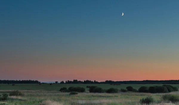 Sonnenuntergang mit einem Stück Mond noch am Himmel — Stockfoto
