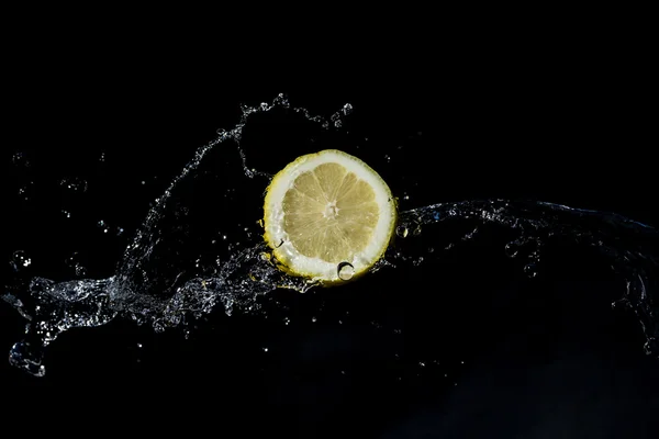 Sliced lemon with water splash with black background Royalty Free Stock Images