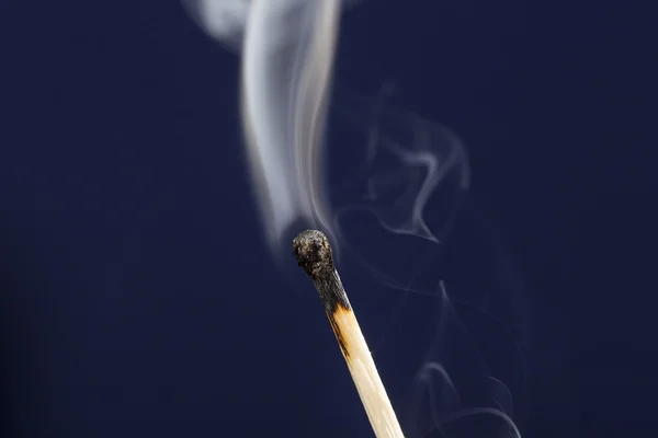Fósforo extinto com fumaça no fundo azul escuro — Fotografia de Stock