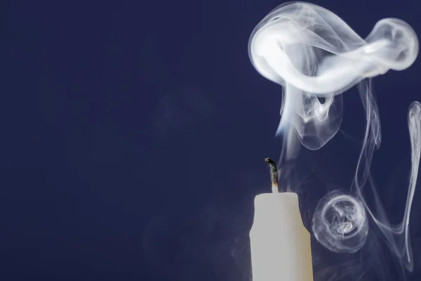 Erlöschte Kerze mit Rauch auf blauem Hintergrund — Stockfoto