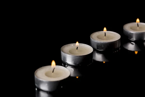Osvětlené čajové svíčky s odrazem na černém pozadí — Stock fotografie