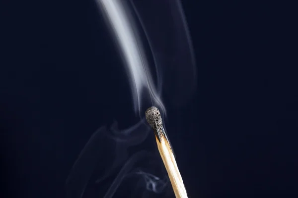Погасшая спичка с дымом на темно-синем фоне — стоковое фото