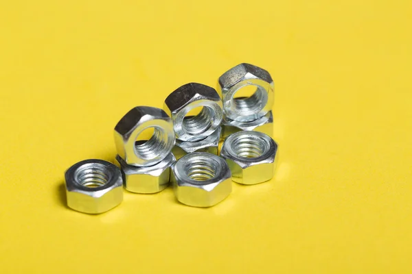 Set of metal nuts on yellow background — Stock Photo, Image