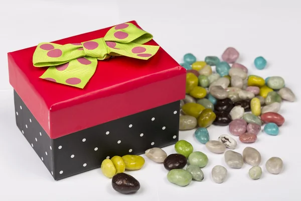 Смешная красная и черная подарочная коробка с зеленой лентой и конфетками — стоковое фото