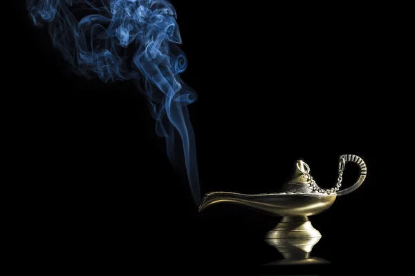 Magic lamp on black background from the story of Aladdin with Genie appearing in blue smoke concept for wishing, luck and magic — Stock Photo, Image