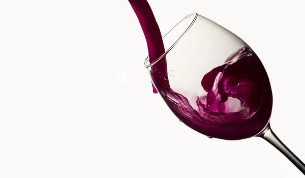 Vinho tinto derramando em um copo de vinho em branco — Fotografia de Stock