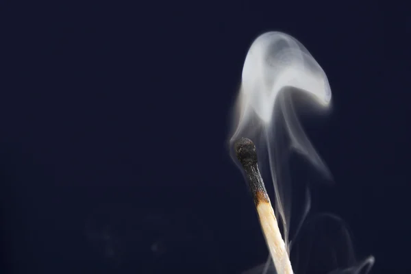 Fósforo extinto com fumaça no fundo azul escuro — Fotografia de Stock