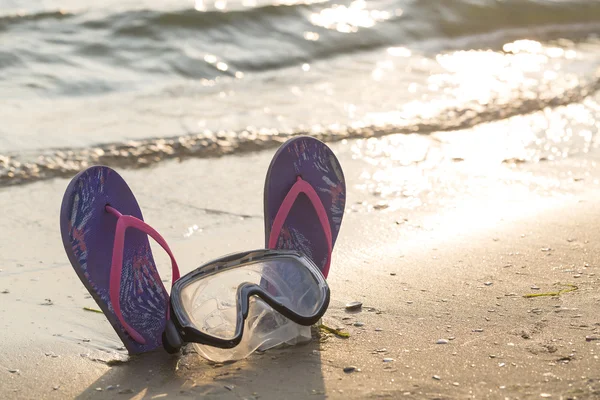 Summer holiday concept. Colorful flip flops with diving mask on the sandy beach during sunset — Stock Photo, Image
