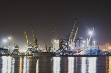 Novorossiysk, Rusya Federasyonu ışıklı kargo liman konteyner terminalleri, kargo gemisi ve Vinçler ve gökyüzü ile gece Panorama görüntüsü