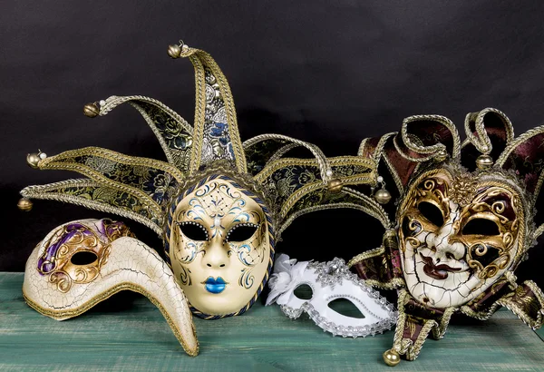 Máscaras de carnaval venezianas na superfície de madeira verde contra fundo escuro — Fotografia de Stock