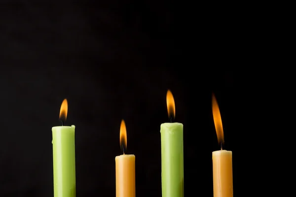 Cuatro velas de colores ardientes sobre fondo negro —  Fotos de Stock