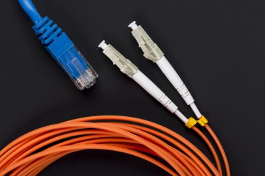Mavi bükülü tel çifti yama kablosu koyu arka plan üzerinde turuncu fiber optik kablo ile
