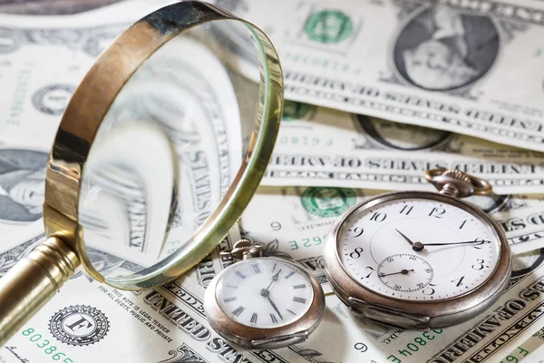 El tiempo es el concepto de finanzas monetarias con viejos relojes vintage, billetes de dólar y lupa —  Fotos de Stock