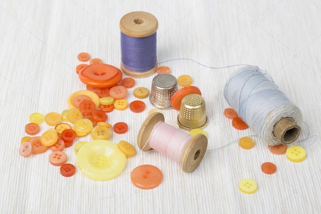 Diferentes carretes de rosca con botones de colores y dedal en la