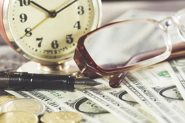 Concepto de finanzas de estilo vintage con gafas, billetes de dólar, reloj retro, monedas y pluma estilográfica —  Fotos de Stock