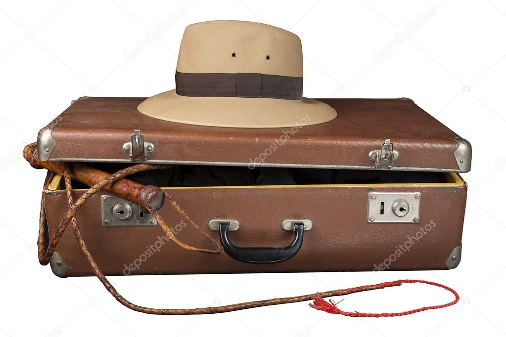 Travel and adventure concept. Vintage brown suitcase with fedora hat and bullwhip isolated on white