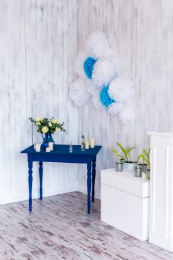 İç tasarım, beyaz çiçekler, beyaz bir ahşap arka plan mavi bir masada mavi bir vazoda gül.