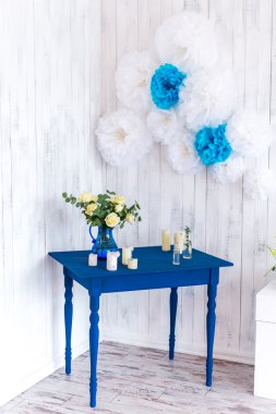 İç tasarım, beyaz çiçekler, beyaz bir ahşap arka plan mavi bir masada mavi bir vazoda gül.