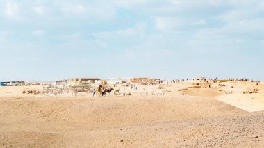 Giza, Mısır - 17 Kasım 2025 - Mısır piramidinin yanındaki küçük bir deve ve ve at kervanı grubunun fotoğrafı güneşli bir günde ve mavi gökyüzünde