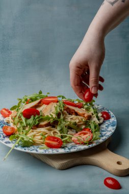 Karides, roka ve domatesli makarna. Çatal bıçaklı kadın elleri