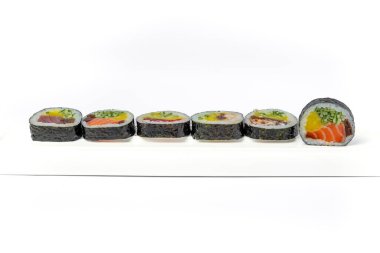 Beyaz arka planda beyaz bir tabakta suşi rulosu karışımı izole edilmiş