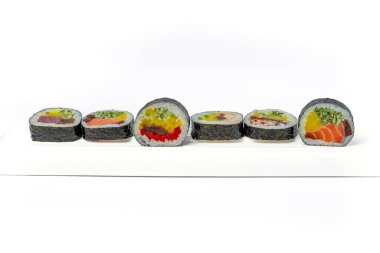 Beyaz arka planda beyaz bir tabakta suşi rulosu karışımı izole edilmiş