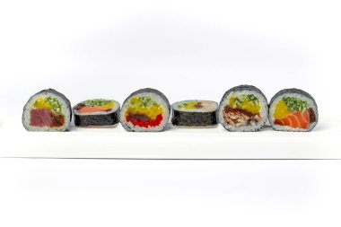 Beyaz arka planda beyaz bir tabakta suşi rulosu karışımı izole edilmiş