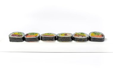 Beyaz arka planda beyaz bir tabakta suşi rulosu karışımı izole edilmiş