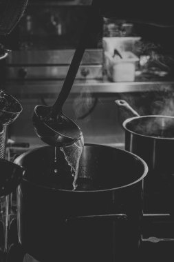 Şef ramen pişirmek için bir tabağa çorba dolduruyor.