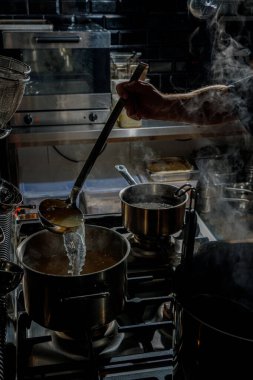 Şef ramen pişirmek için bir tabağa çorba dolduruyor.