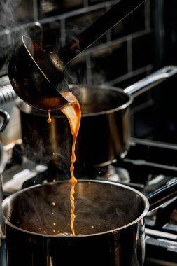 Şef ramen pişirmek için bir tabağa çorba dolduruyor.