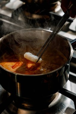 Profesyonel bir mutfakta erişteye karides ekliyorum.