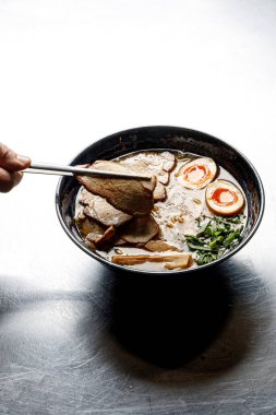 Şef arka planda bir tabak ramen yiyor.