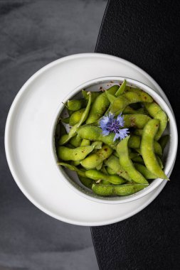 Siyah arka planda beyaz tabakta yeşil bezelye lokantası.