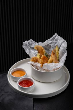 Menü için beyaz bir tabakta soslu tempura içinde karidesler.